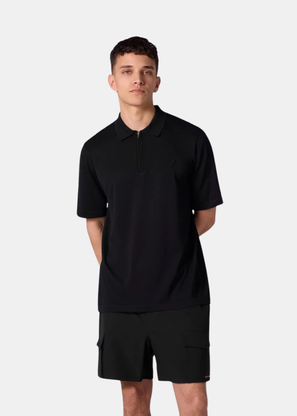 Vue de face d'un homme portant le polo oversize en maille noir Gertrude Jude avec un short assorti en maille noir.