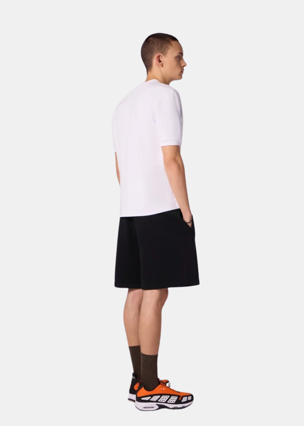 Vue de profil d'un homme portant le short en maille noir Gertrude Isidore avec des chaussettes et baskets.