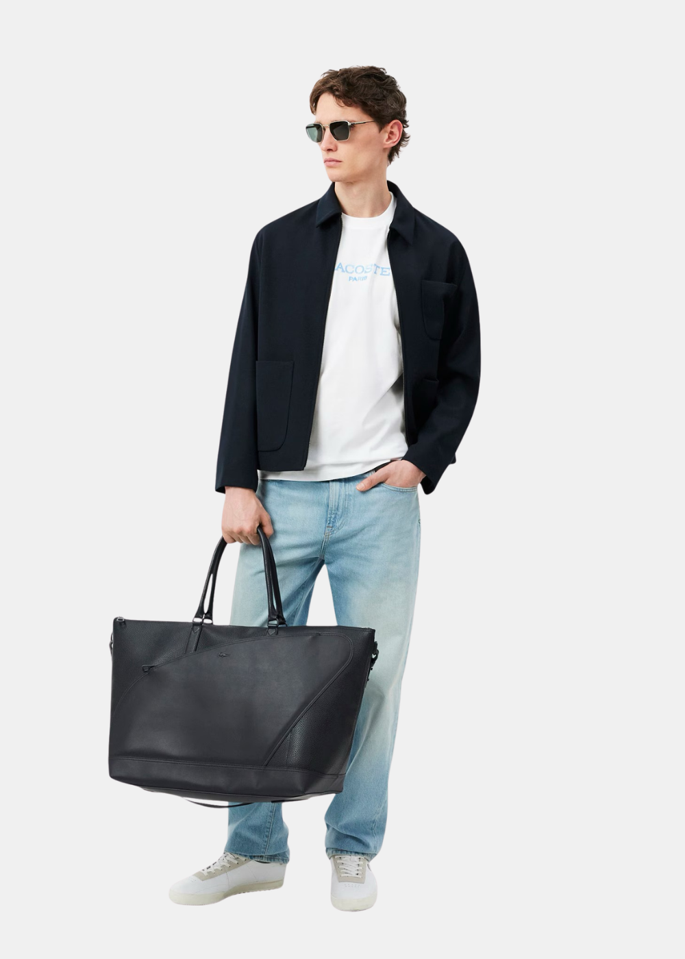 Look complet avec t-shirt Lacoste blanc, surchemise bleu marine, jean clair et grand sac cabas noir en cuir.