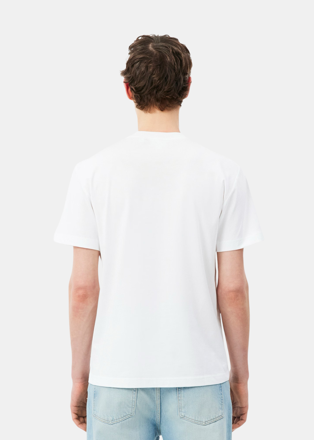 Vue de dos d'un homme portant le t-shirt Lacoste blanc à manches courtes et un jean bleu clair sur fond blanc.
