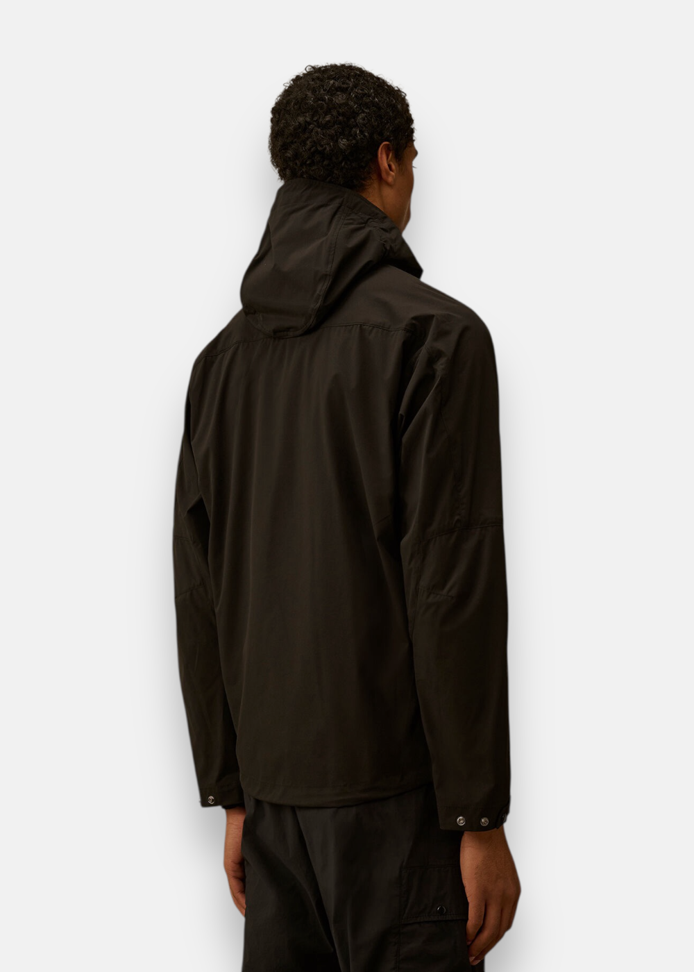 Homme de dos portant la veste noire C.P. Company Pro-Tek avec capuche.