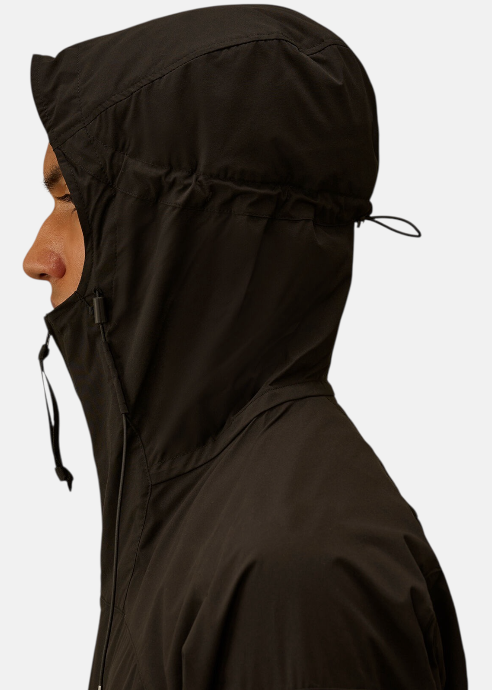 Gros plan de profil sur la capuche technique ajustable de la veste noire C.P. Company.