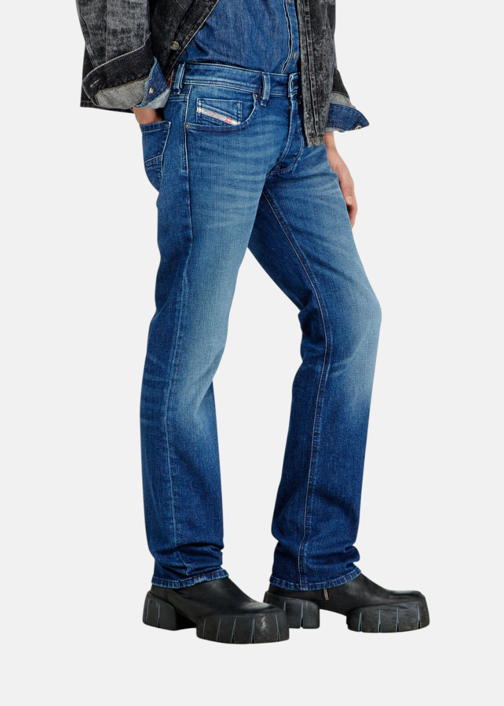 Vue de profil du jean bleu Diesel 1985 Larkee porté par un mannequin, soulignant la jambe droite et le détail de la petite poche gousset logotée