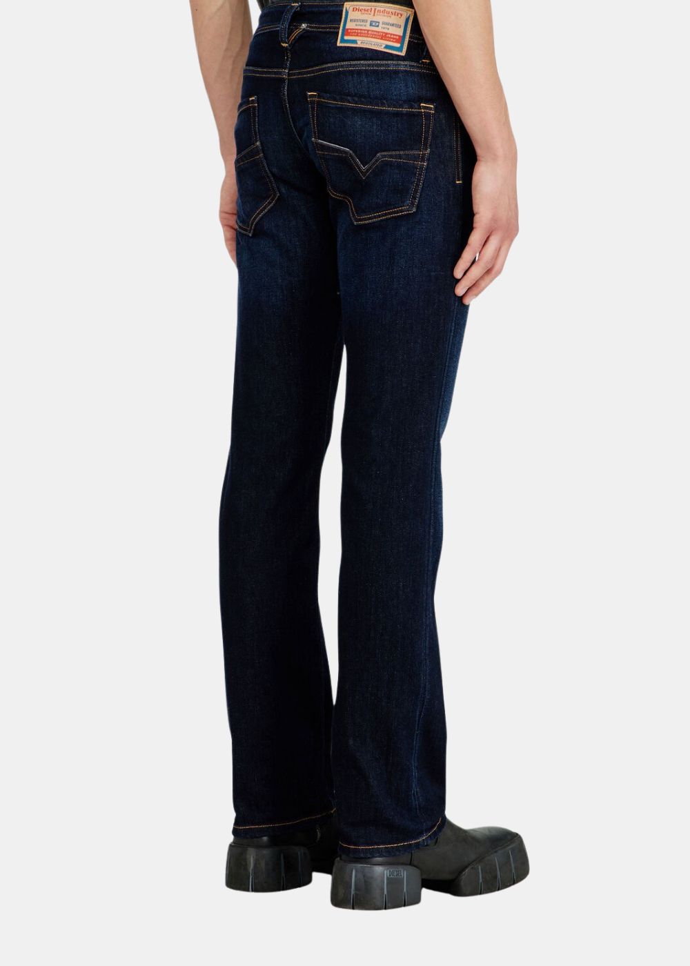 Vue arrière des jambes du mannequin portant le jean bleu regular Diesel 1985 Larkee avec poches surpiquées.