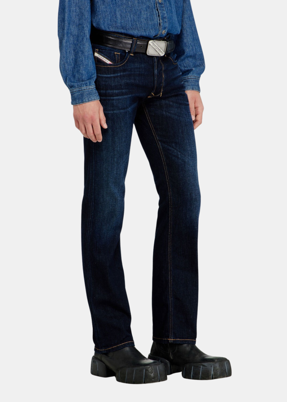 Vue de profil des jambes du mannequin portant le jean bleu regular Diesel 1985 Larkee et des baskets noir.