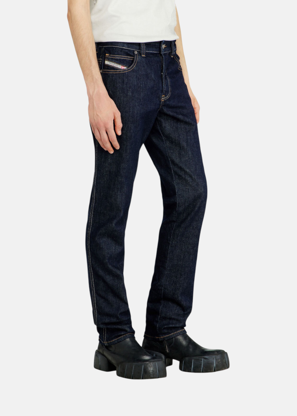 Jean bleu foncé Diesel 1993 D-Vyl de coupe slim et taille moyenne, porté par un mannequin de profil avec des bottines en cuir noir.