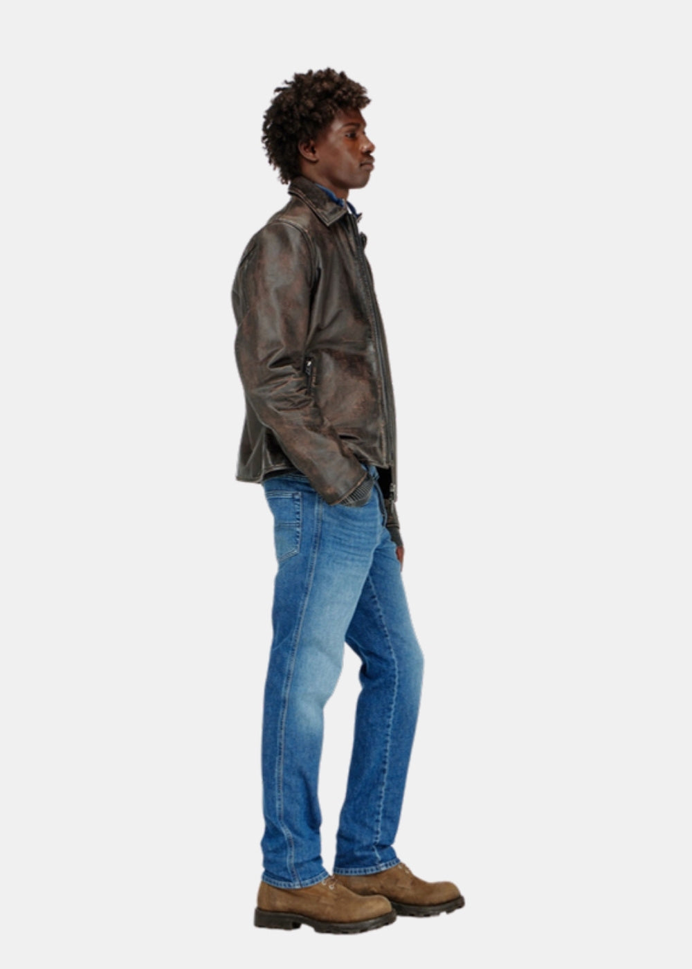 Porté de profil d'un jean slim bleu Diesel D-vyl 1993 avec blouson en cuir brun et bottines, coupe fine sur la jambe.