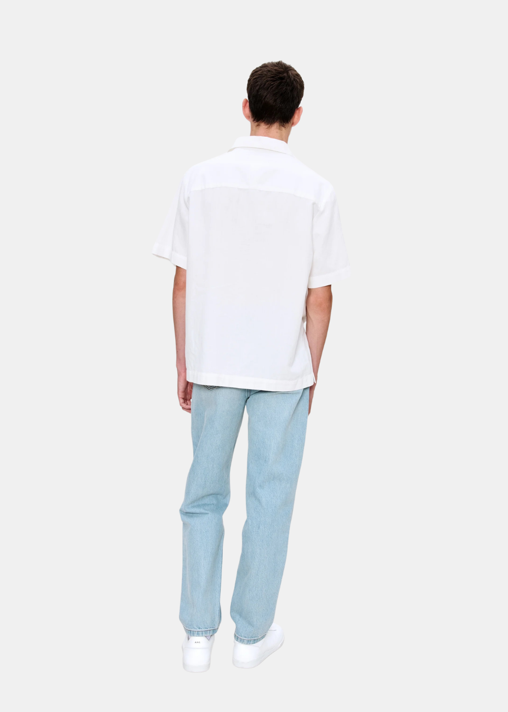 Silhouette de dos du mannequin portant le jean bleu clair A.P.C. Martin coupe droite ample et une chemise blanche