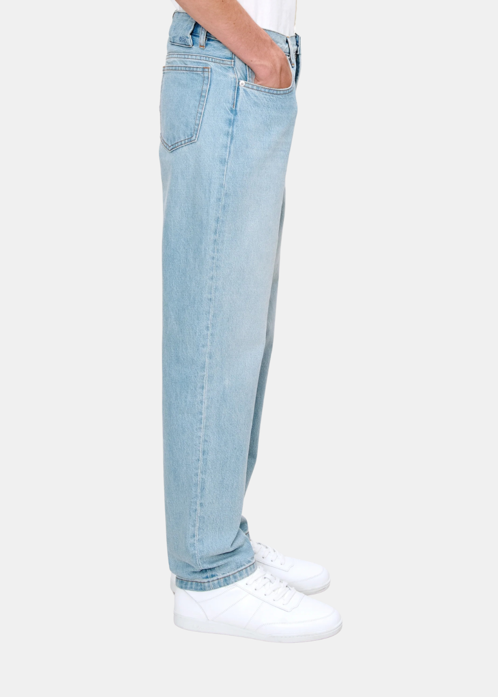 Plan de profil moyen cadré sur les jambes montrant la coupe et la poche arrière du jean bleu clair A.P.C.