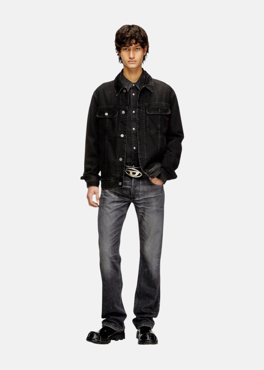Silhouette complète montrant un mannequin avec le jean gris Diesel 1985 Larkee, une chemise noire, une veste en denim noir et des chaussures en cuir brillant