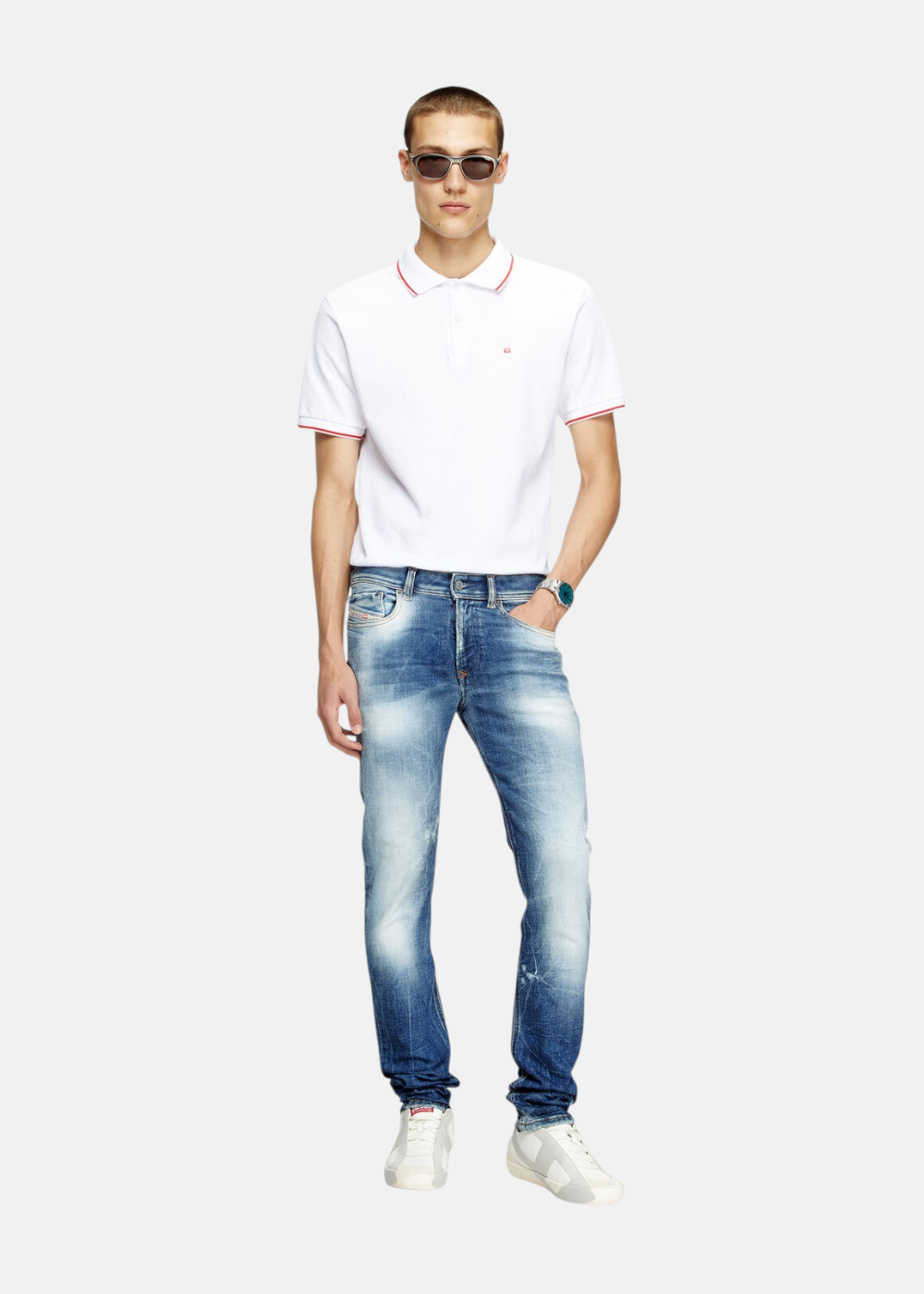 Homme portant le Jeans Diesel 1979 Sleenker skinny bleu foncé avec un polo blanc et des baskets. Look complet de face.