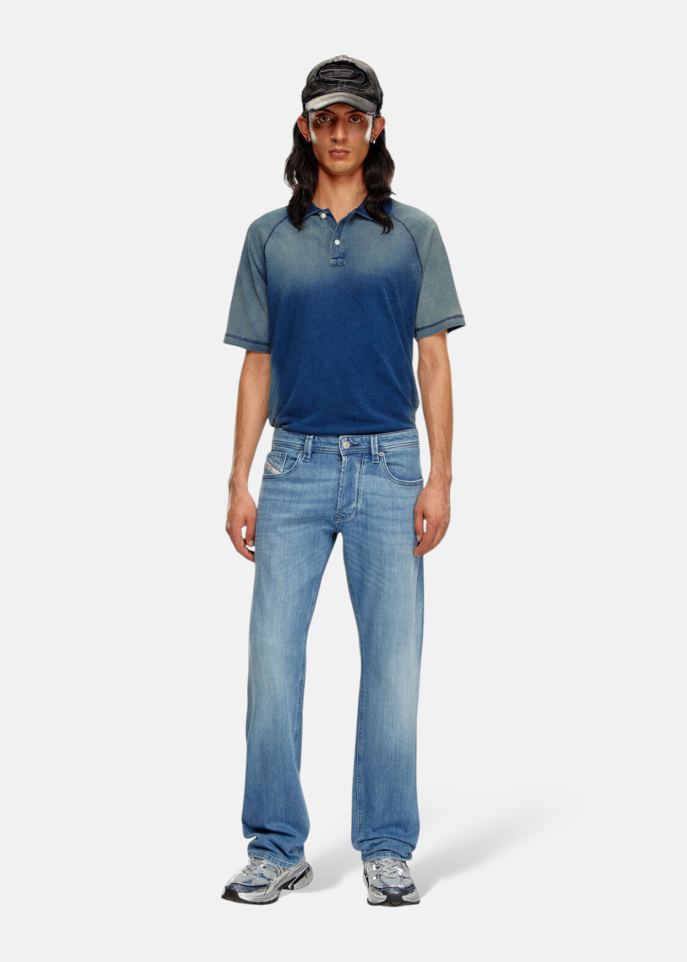 Homme portant le Jeans Diesel 1985 Larkee regular bleu avec un polo et une casquette, look complet.