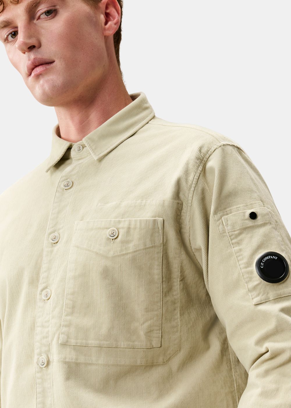 Gros plan sur la nouvelle lentille mat NFC C.P. Company et la texture en velours côtelé beige.