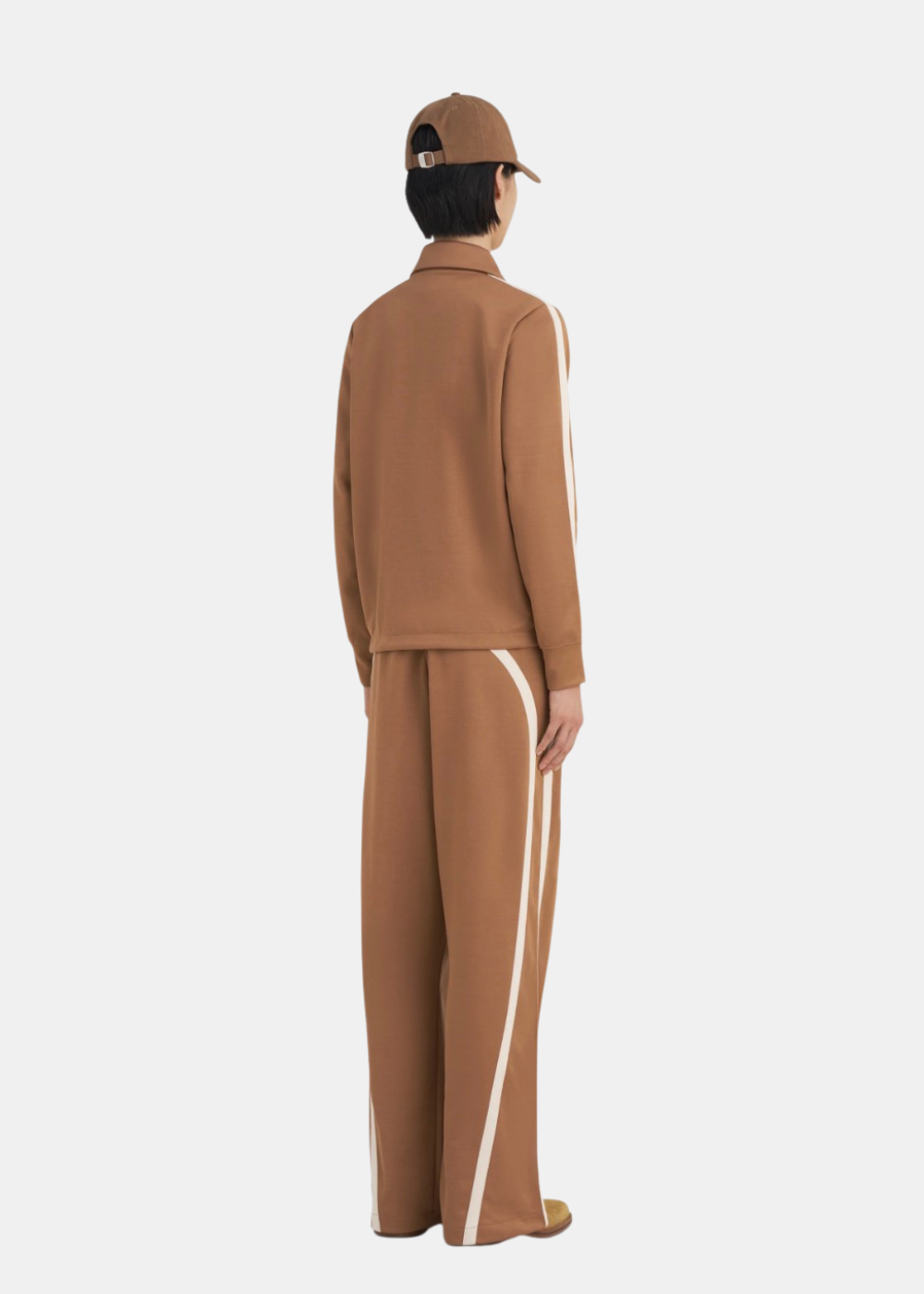 Mannequin femme portant la veste de survêtement Études Studio marron de dos avec bandes appliquées sur les manches ainsi que le pantalon du même  style que la veste .