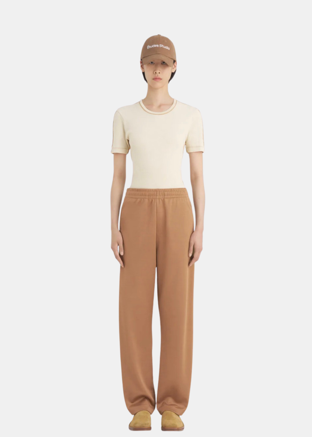 Femme portant le pantalon de survêtement Études Studio marron avec un t-shirt beige, vue de face.