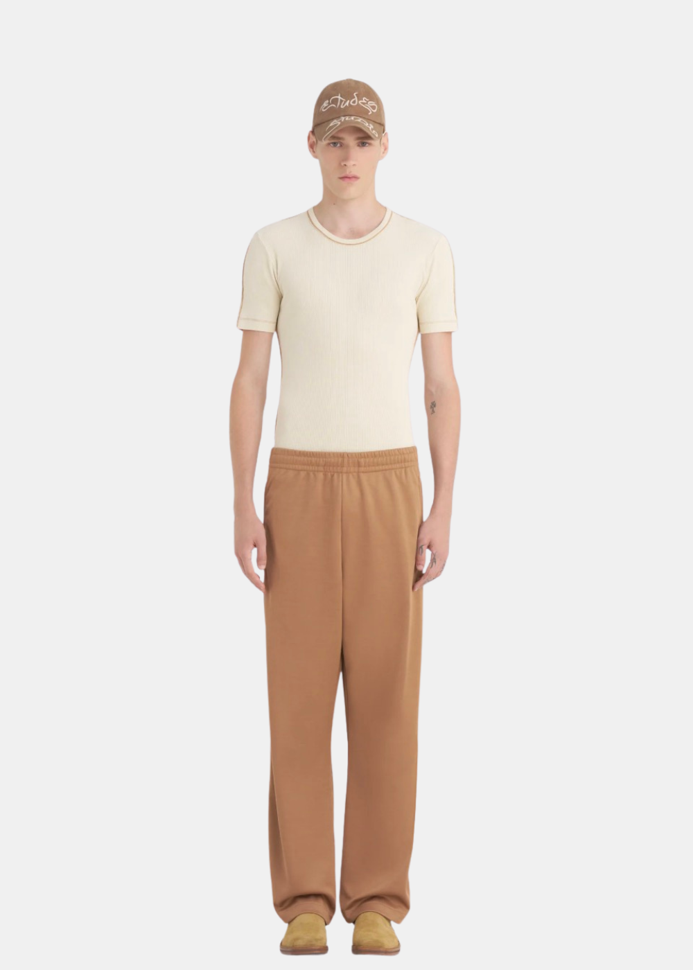 Homme portant le pantalon de survêtement Études Studio marron avec un t-shirt beige anthracite, vue de face.