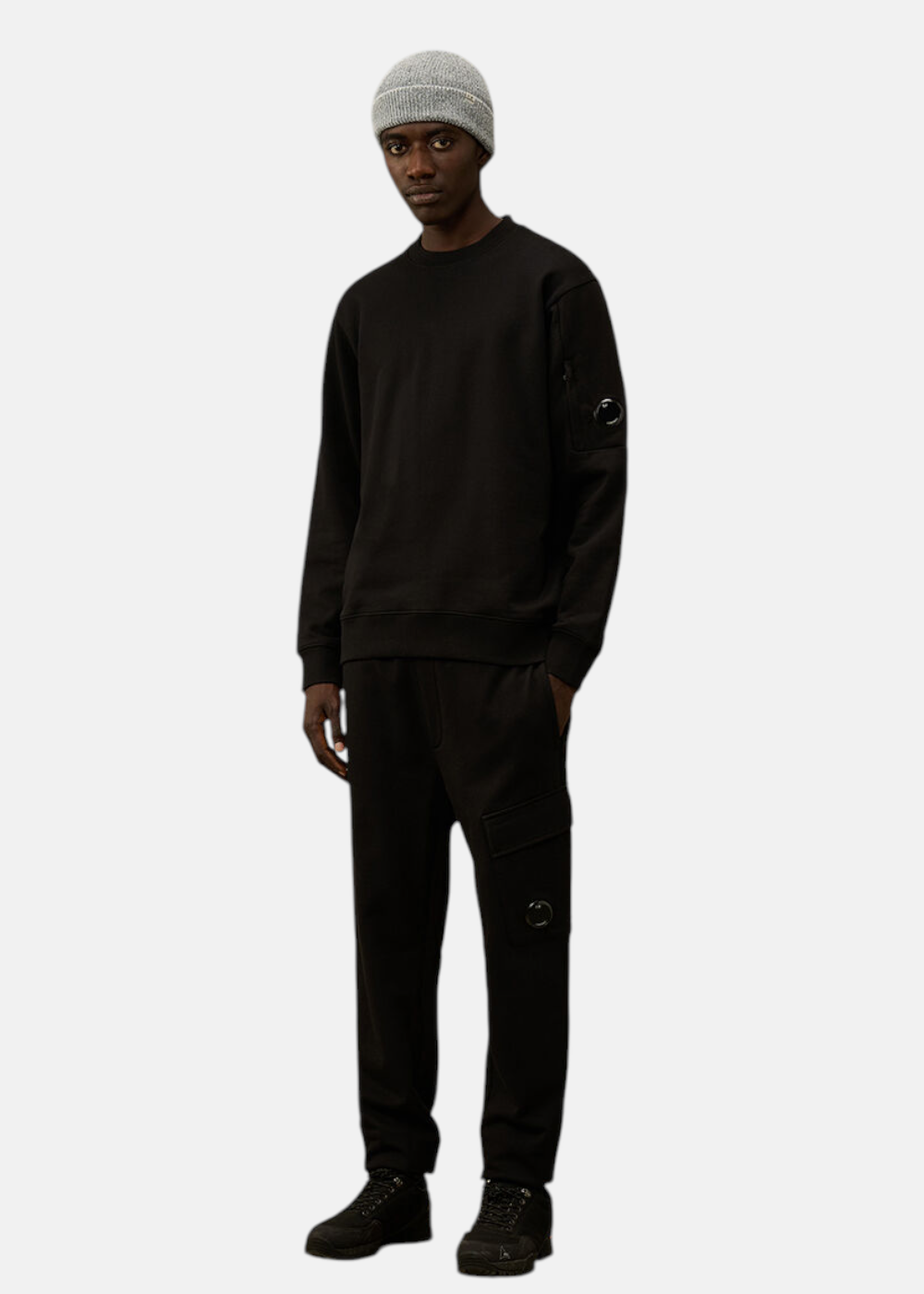 Look complet homme, sweat C.P. Company col rond noir en molleton avec un pantalon et un bonnet gris.