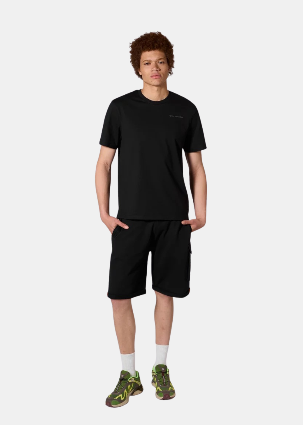 Mannequin homme de face portant le t-shirt noir Gertrude, un short noir, des chaussettes hautes blanches et des baskets vertes.