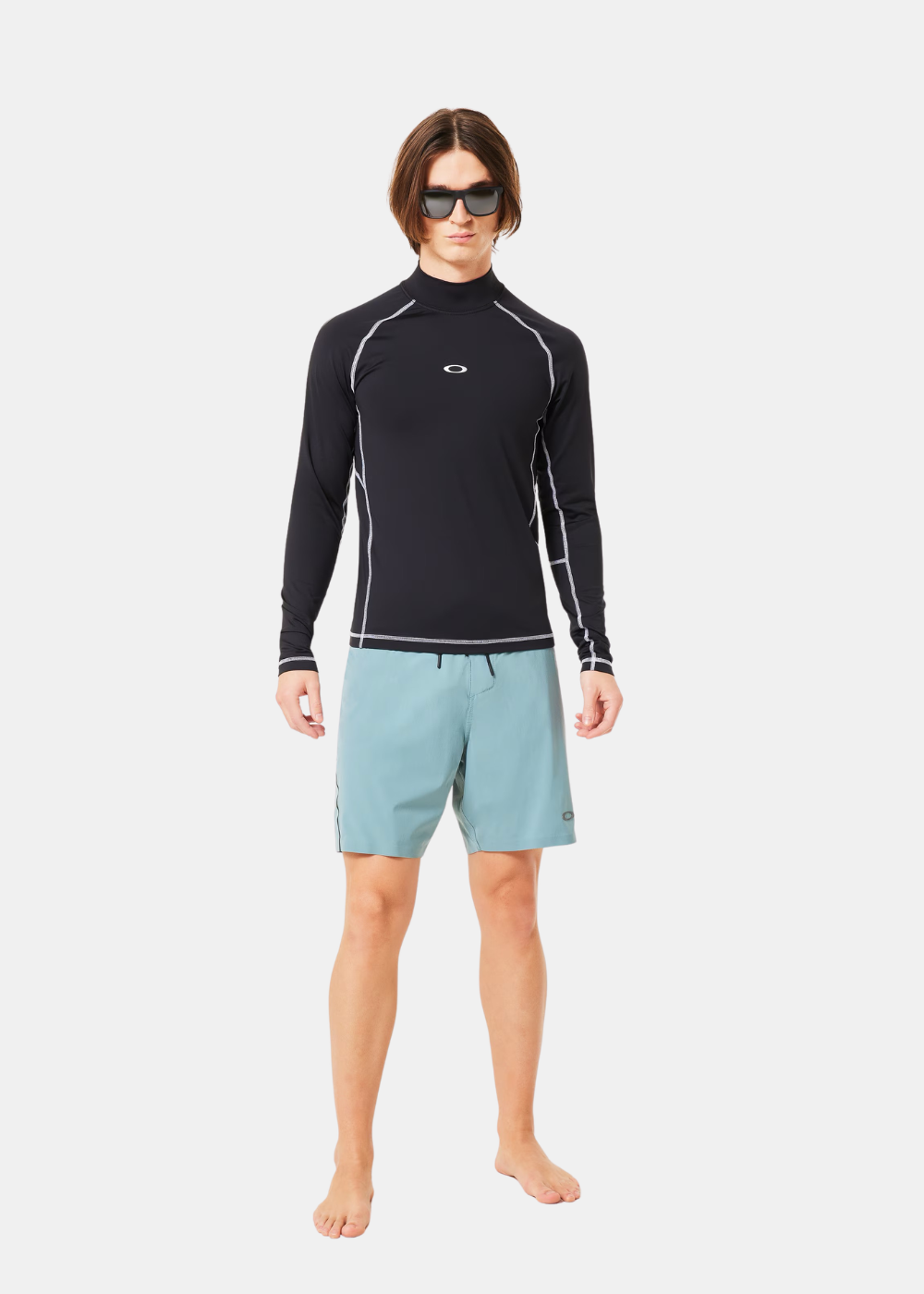 Homme portant le rashguard noir Oakley, un short de sport bleu.