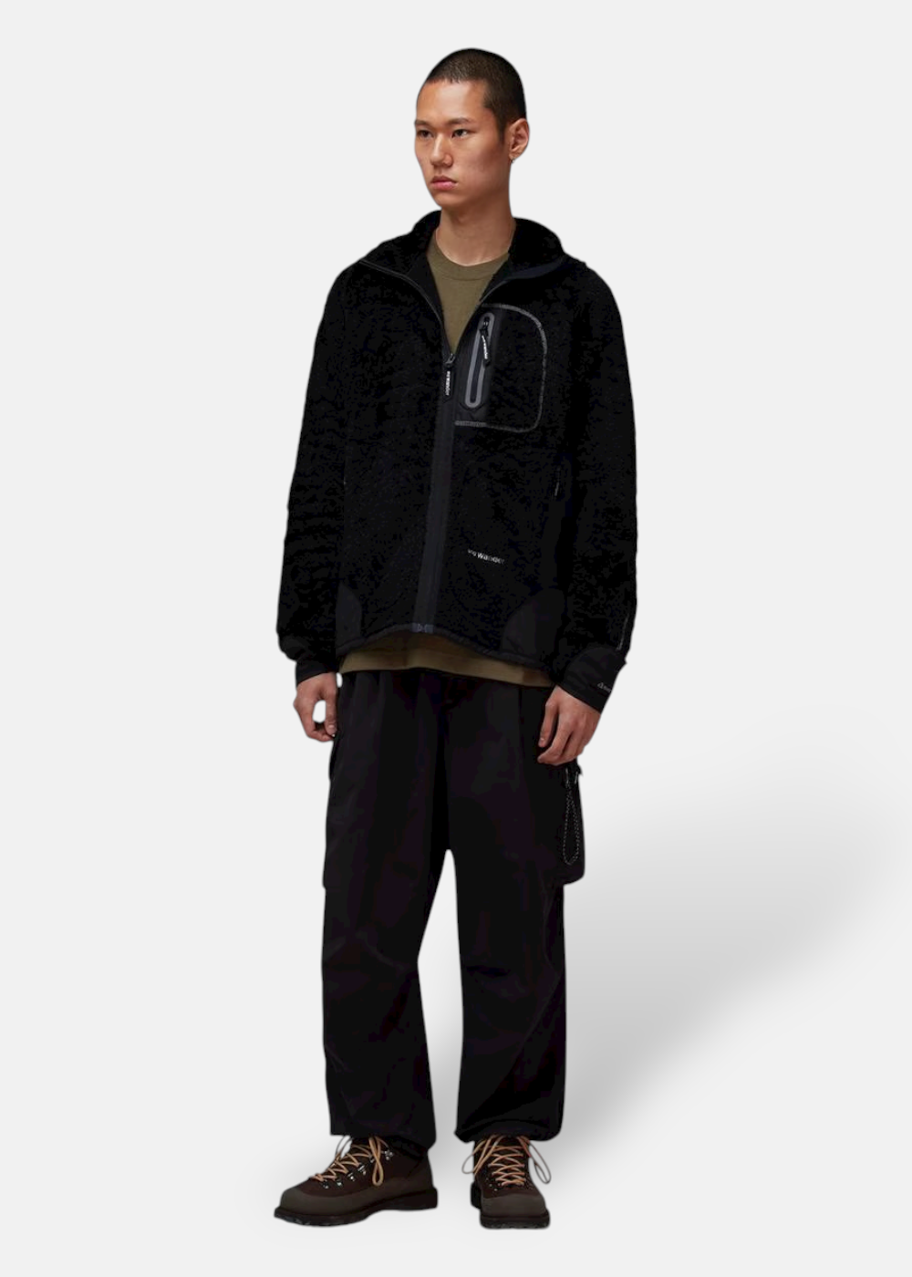 Look complet homme : Veste polaire And Wander High Loft noire avec un T-shirt vert kaki et un pantalon noir.