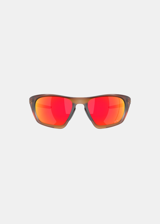 Packshot de face des lunettes Oakley Lateralis Mbappé, mettant en valeur la forme enveloppante de sa structure marron clair et le reflet éclatant rouge orangé de ses verres miroirs Prizm Ruby avec les initiales KM