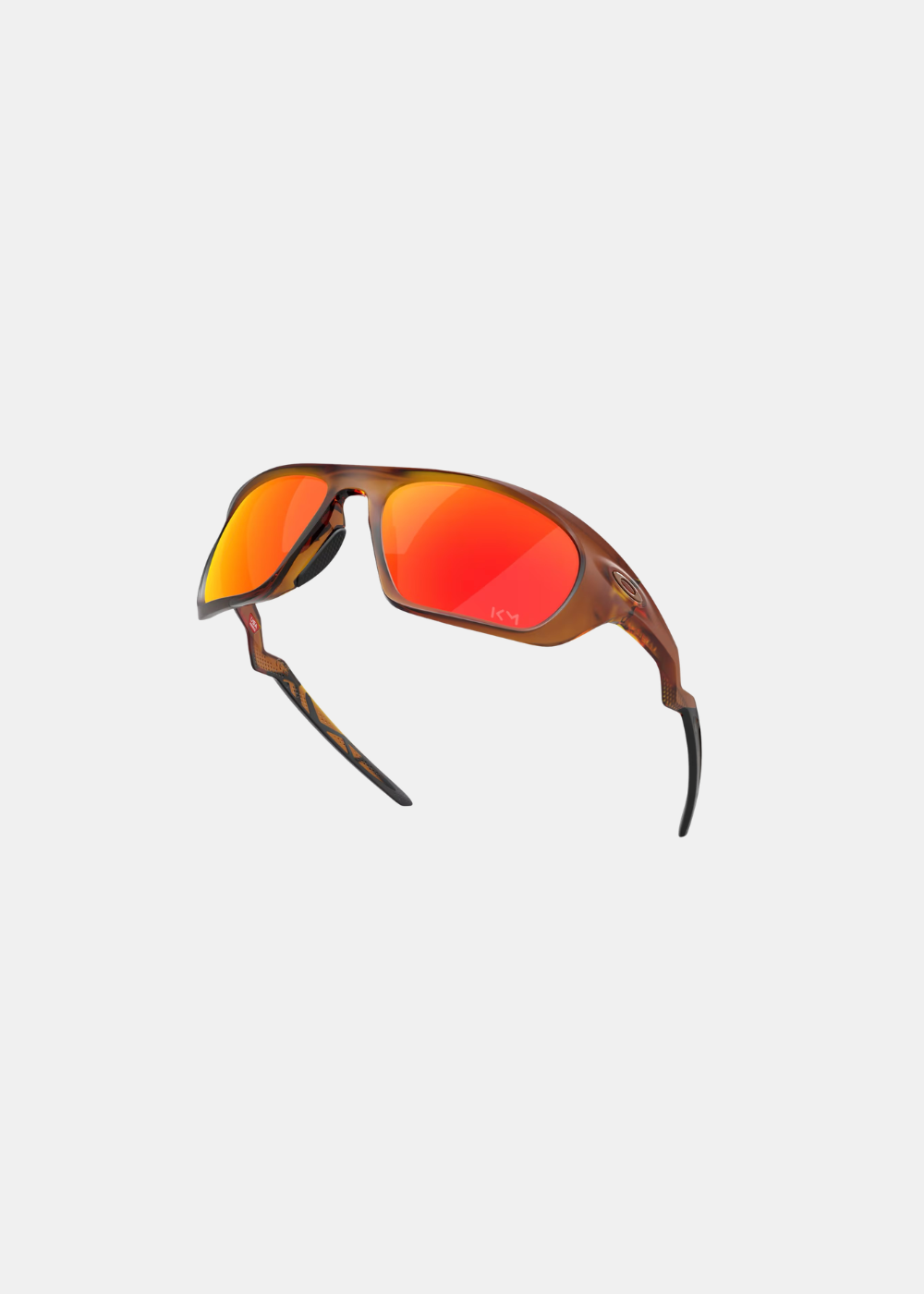 Vue en perspective et surélevée des lunettes Oakley Lateralis Mbappé, soulignant le galbe ergonomique de la monture translucide marron et les plaquettes de nez adhérentes en caoutchouc noir