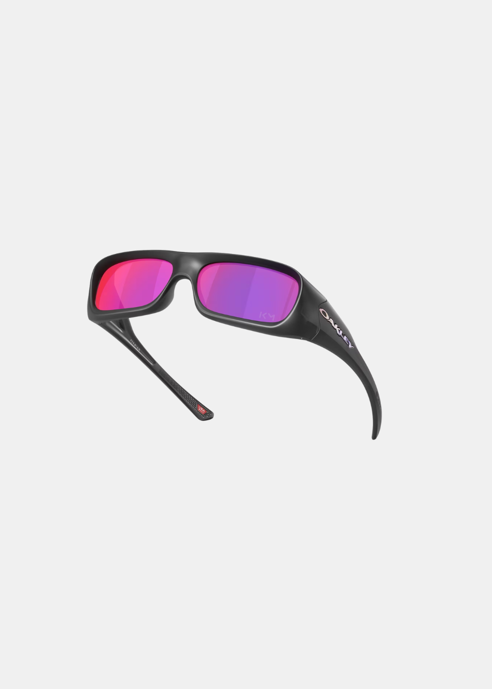 Vue en perspective et surélevée des lunettes Oakley Permian Mbappé, soulignant l'ergonomie galbée de la monture mate, la courbure des branches protectrices et les reflets des verres Prizm Road