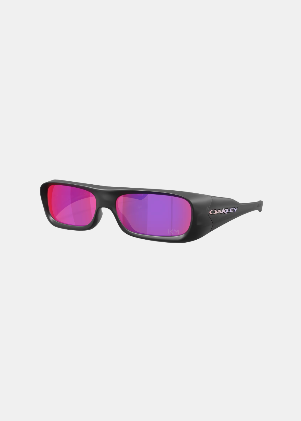 Packshot de trois-quarts face sur fond gris des lunettes Oakley Permian Kylian Mbappé, montrant la monture noire mate enveloppante, le logo Oakley chromé aux reflets irisés sur la branche et les verres Prizm Road violets avec la signature KM discrète