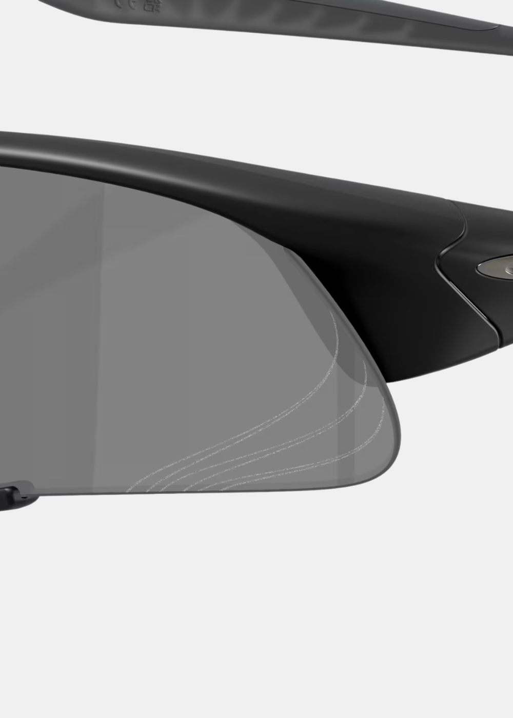 Gros plan détaillé sur le verre Prizm Black des lunettes Oakley Suture Jacket, mettant en évidence les fines lignes graphiques gravées au laser sur la partie inférieure et la finition mate de la monture