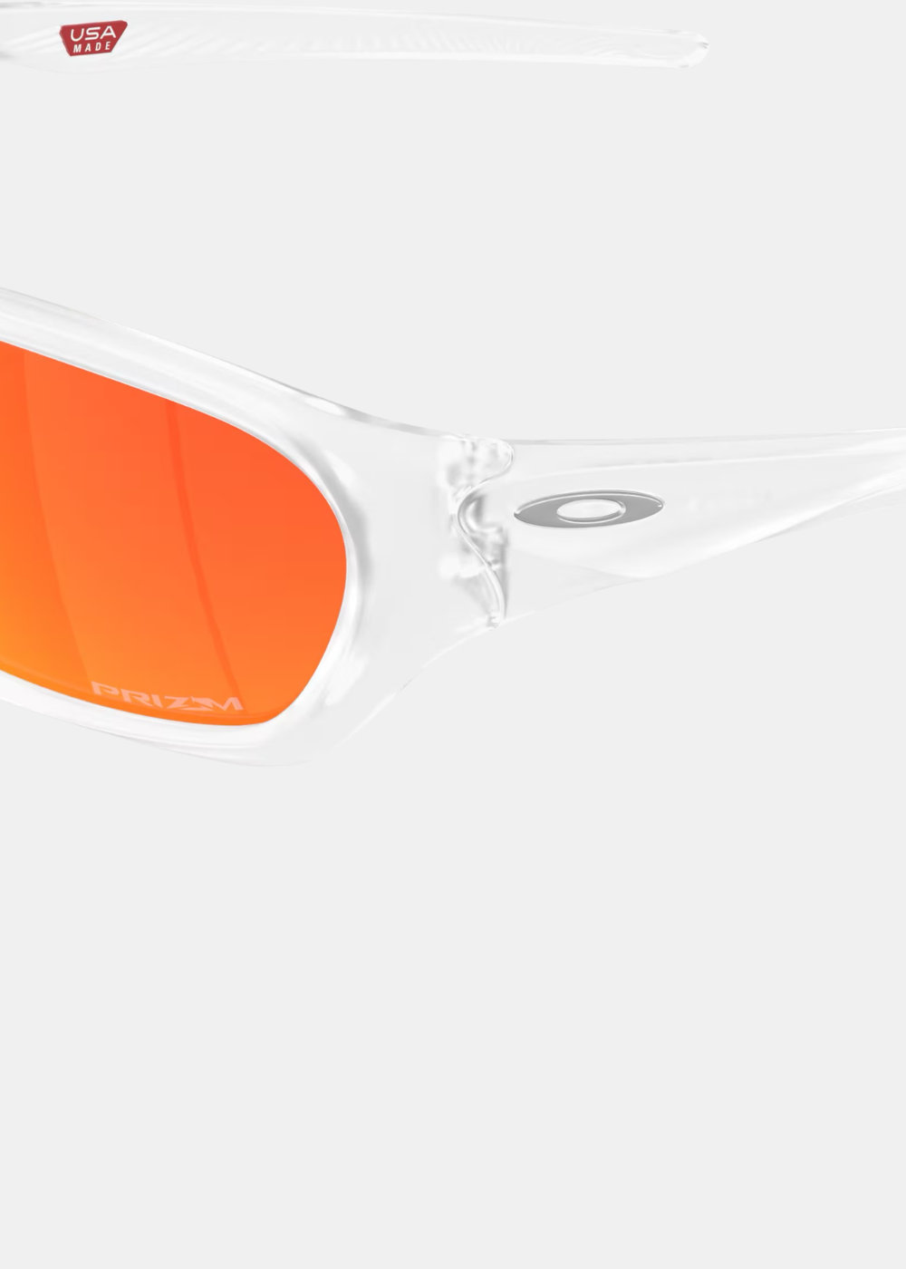 Gros plan détaillé sur le côté gauche des lunettes Oakley Terraforma, mettant en valeur la finition injectée transparente de la charnière, le logo métallique ellipse Oakley incrusté et l'inscription Prizm discrète gravée sur le verre miroir orange