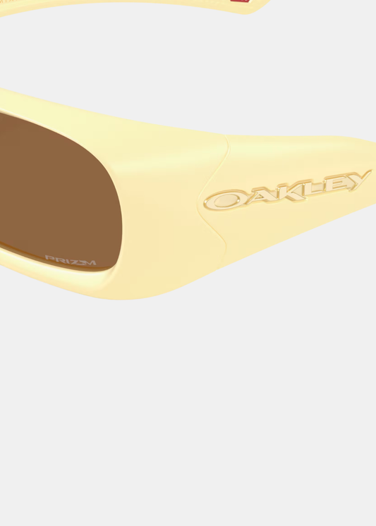Plan rapproché sur la branche jaune milkshake affichant le logo OAKLEY doré et le verre Prizm Bronze.