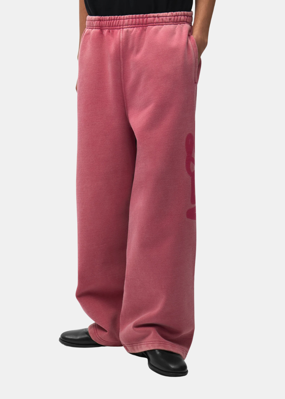 Vue de profil du pantalon de sport rouge délavé Arte Antwerp révélant l'imprimé logo style pochoir.