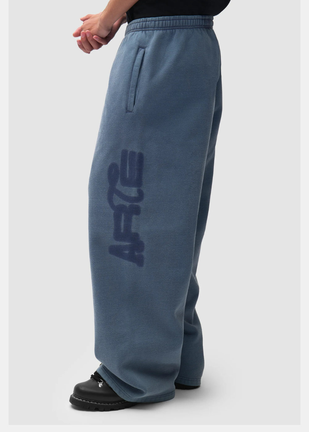 Gros plan sur le bas du pantalon de jogging ample rouge délavé Arte Antwerp porté avec des chaussures noires.