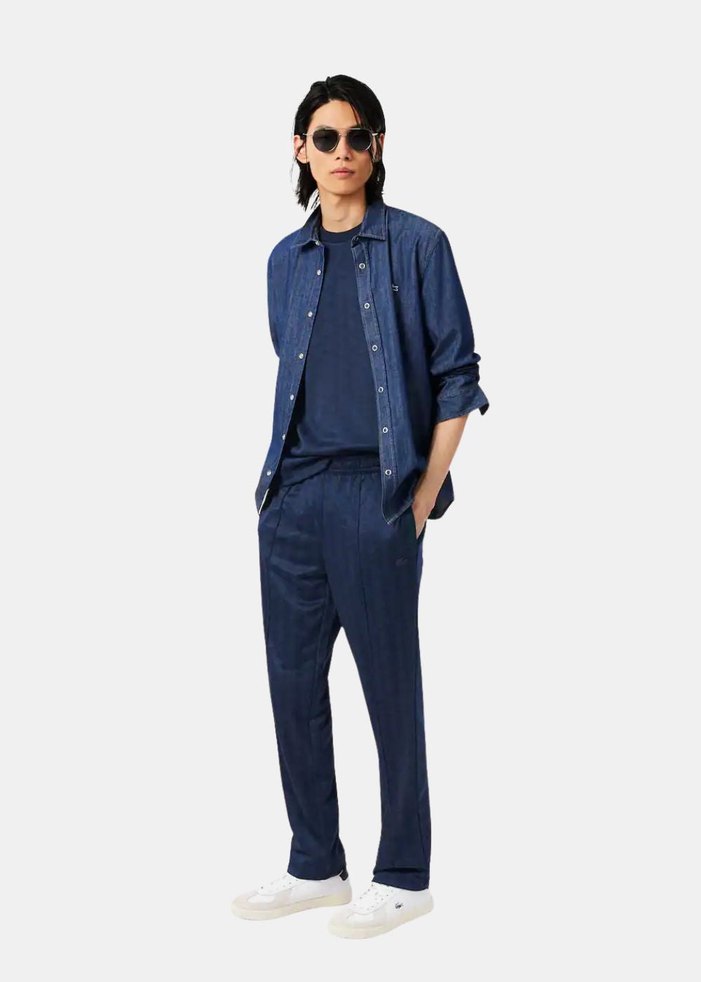 Mannequin portant le pantalon de survêtement Lacoste bleu marine avec une surchemise en denim assortie.