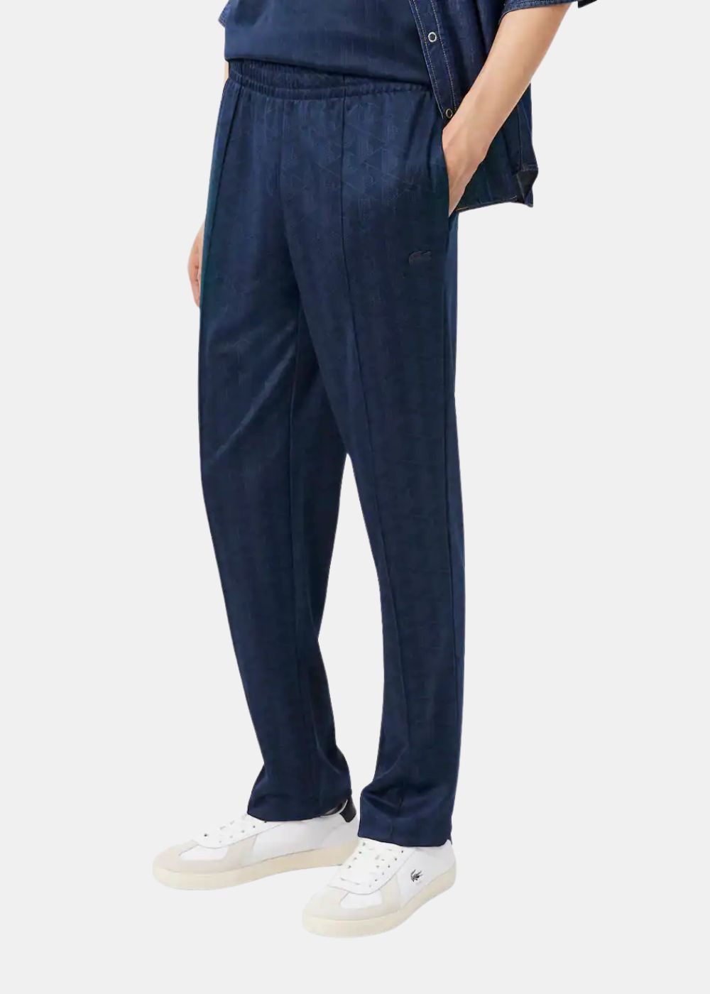Gros plan porté sur la coupe droite et les détails du pantalon de survêtement Lacoste bleu marine.