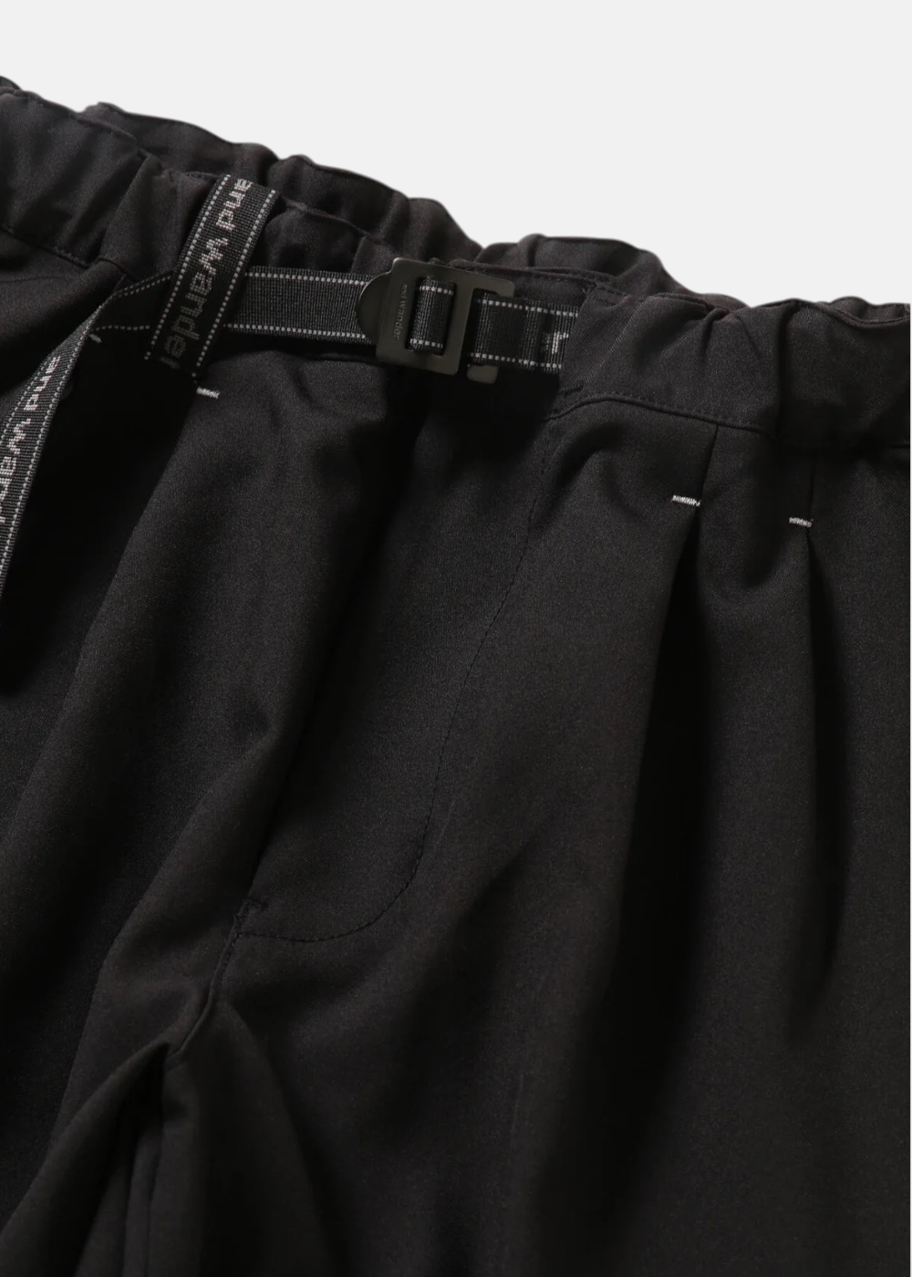 Gros plan sur la taille élastique et la ceinture à boucle intégrée logotée And Wander.