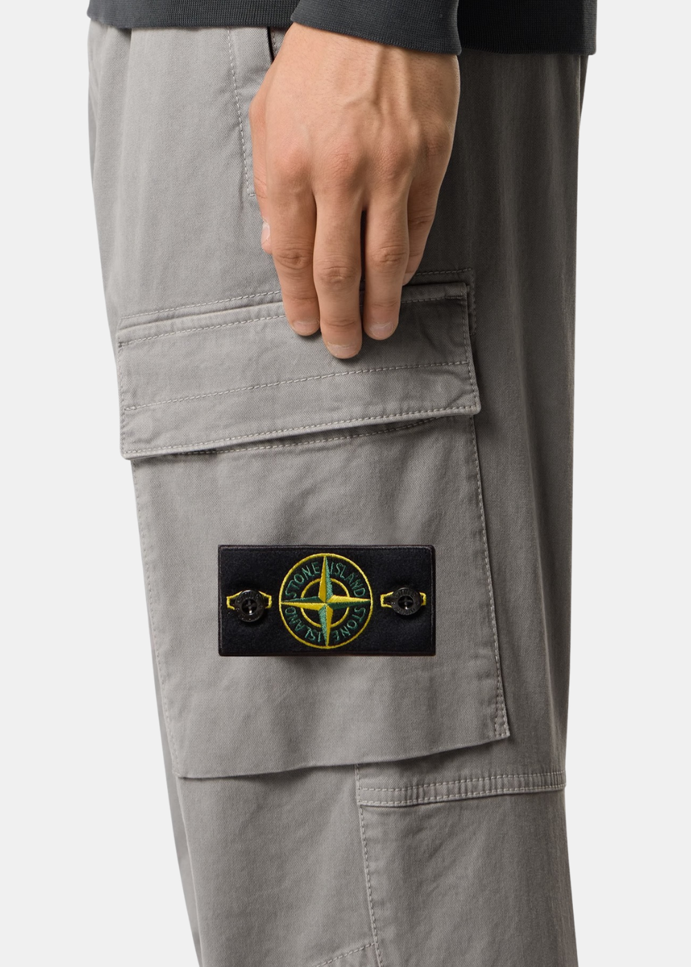 Gros plan sur la poche cargo avec badge Compass Stone Island sur la jambe d'un pantalon gris porté