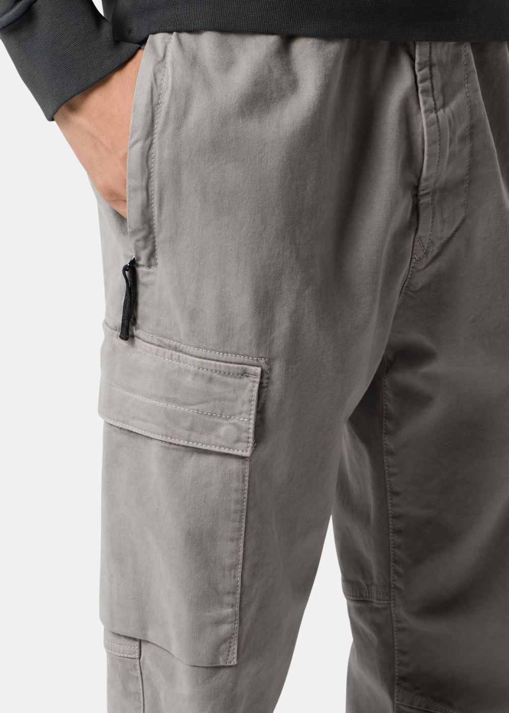 Gros plan sur la poche latérale zippée et la poche cargo à rabat d'un pantalon gris Stone Island