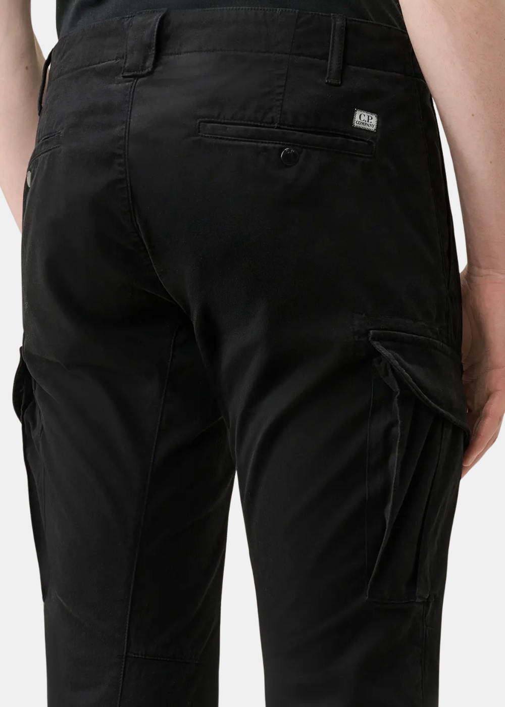 Zoom de dos sur un pantalon cargo noir en satin de coton CP Company avec une petite étiquette logo blanche brodée sur la poche arrière