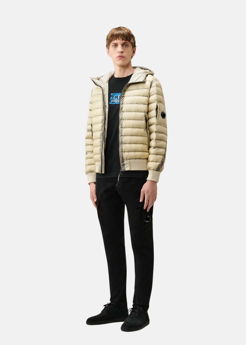 Silhouette entière d un mannequin en pantalon cargo noir CP Company combiné avec un tee shirt noir et une doudoune beige à capuche