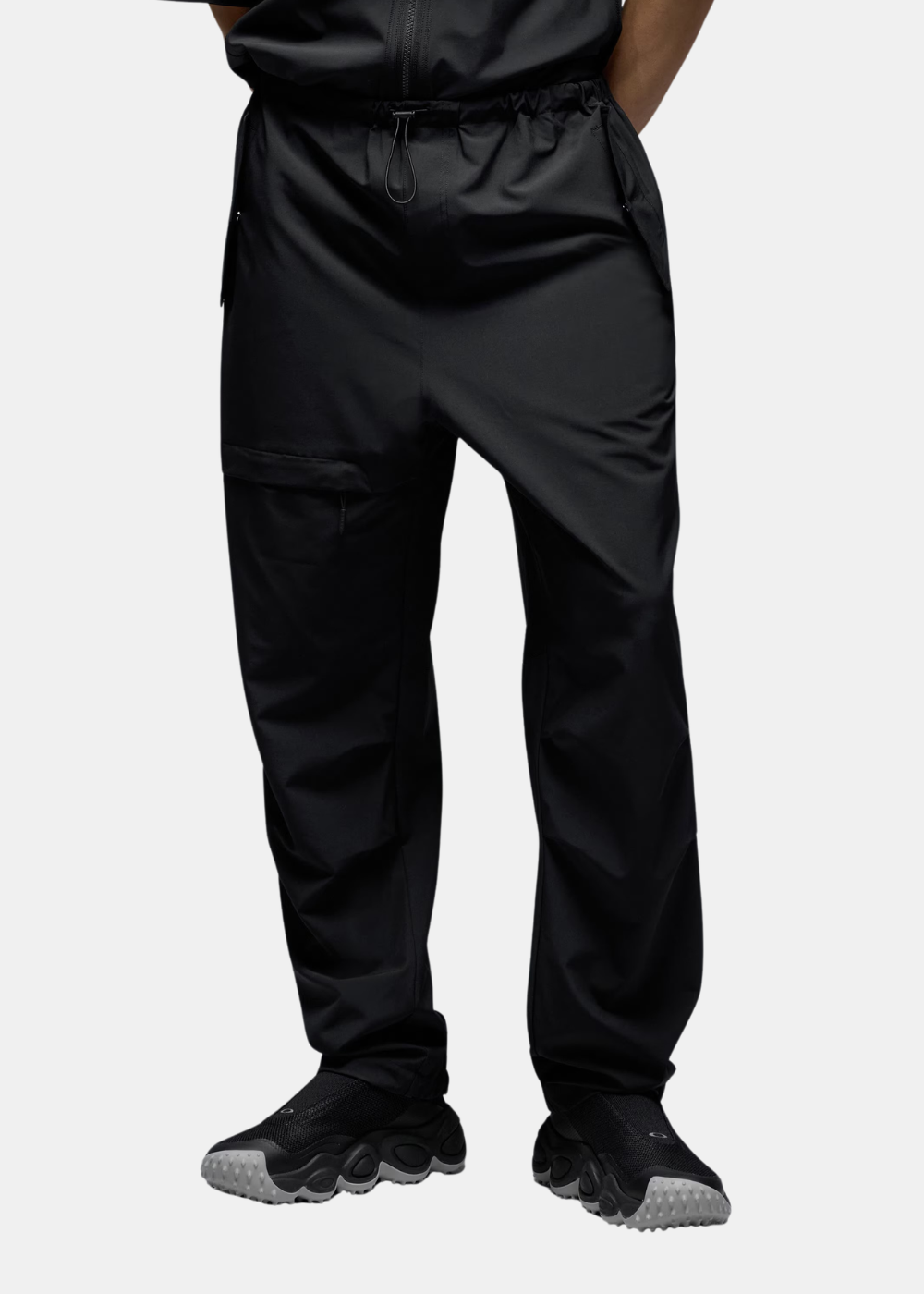 Vue portée des jambes du pantalon noir Oakley montrant la coupe ample et les sneakers noires.