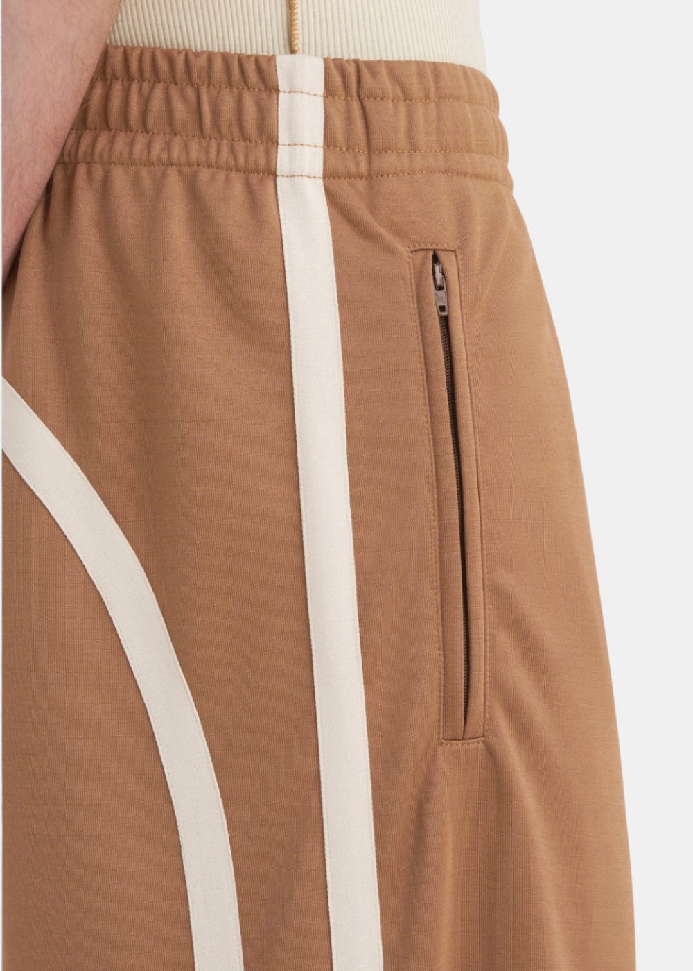 Zoom sur la taille et les bandes et le haut du pantalon Études Studio marron porté par un homme.