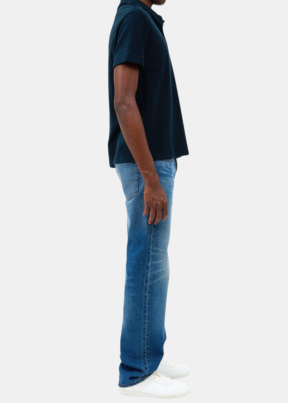 Mannequin de profil portant le polo marin APC Julian en éponge de coton biologique, associé à un jean bleu et des baskets blanches.