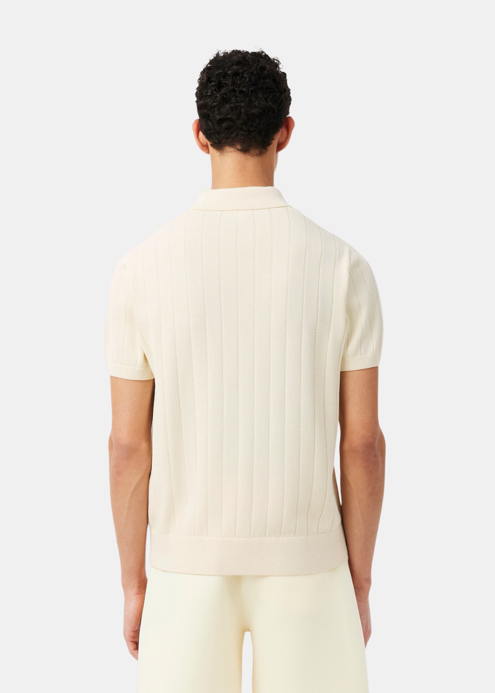 Vue de dos d'un homme portant le polo Lacoste beige, soulignant la texture de la maille côtelée.