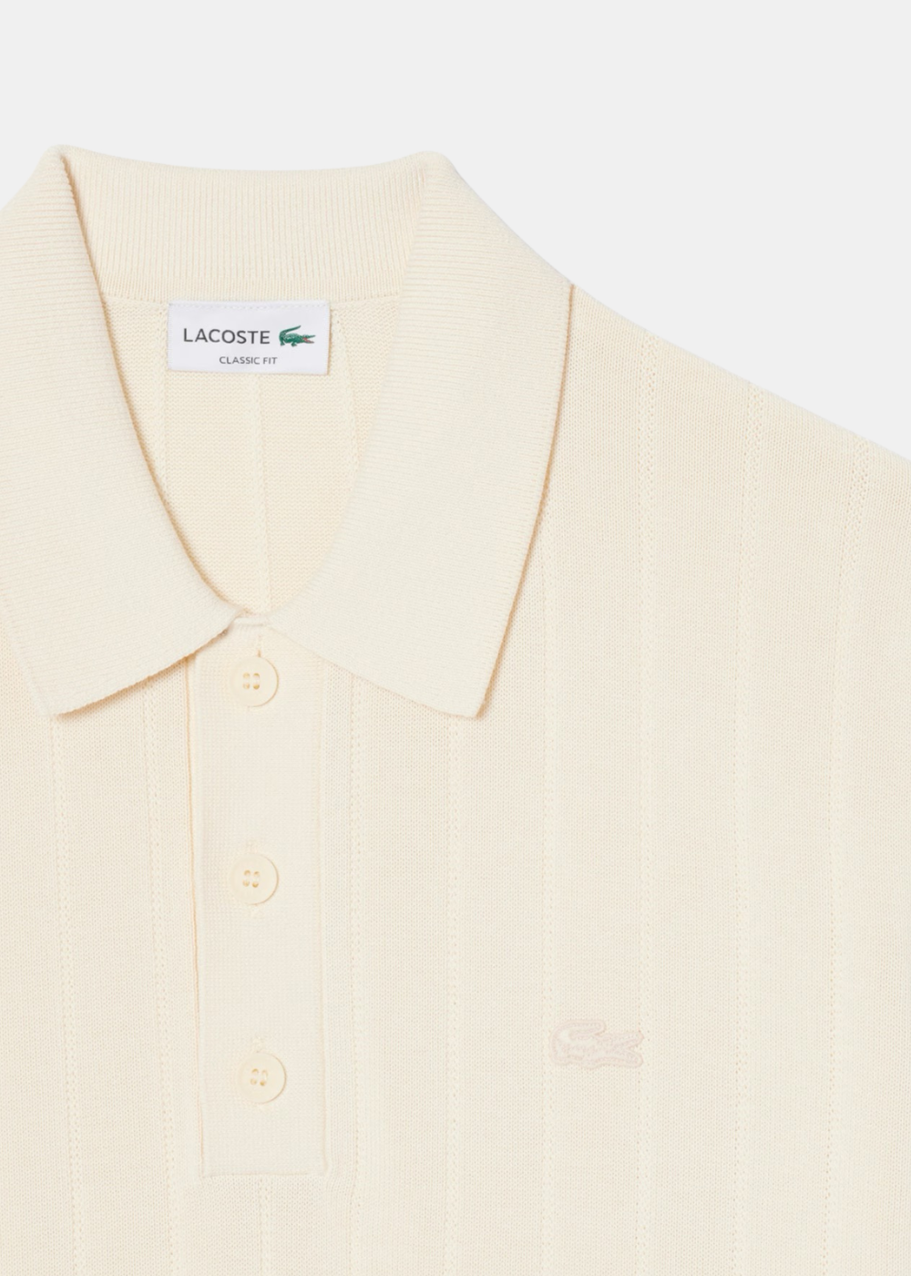 Zoom sur col polo logo croco brodé ton sur ton sur la poitrine d'un polo beige côtelé.