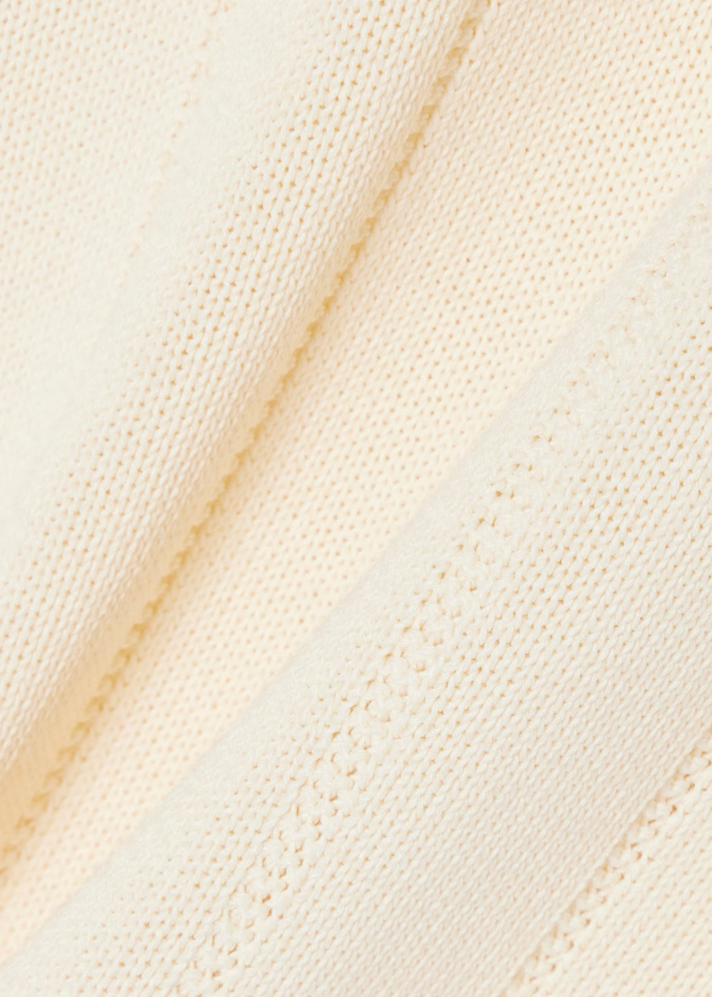 Gros plan sur la texture rayée de la maille côtelée fluide du polo Lacoste beige.
