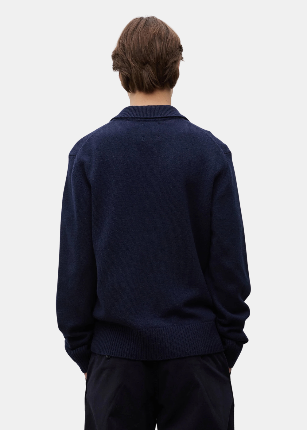 Vue de dos d un mannequin portant le polo Norse Projects Anholt bleu marine et un pantalon sombre