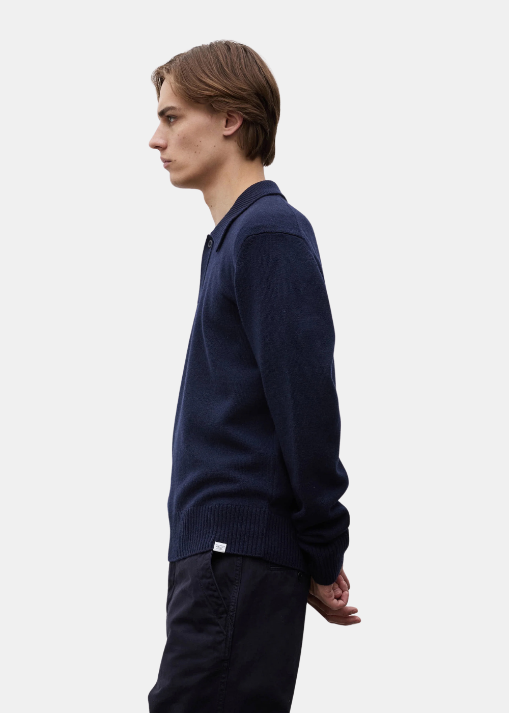 Vue de profil d un mannequin portant le polo Norse Projects Anholt marine avec étiquette au bas