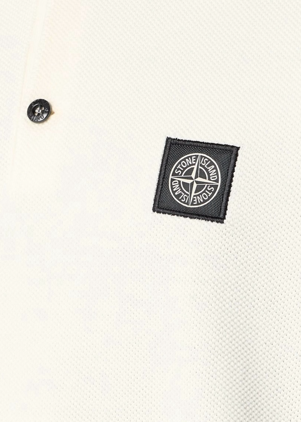 Gros plan sur la poitrine du polo Stone Island blanc montrant la texture du tissu Micro Stitch et le patch logo.