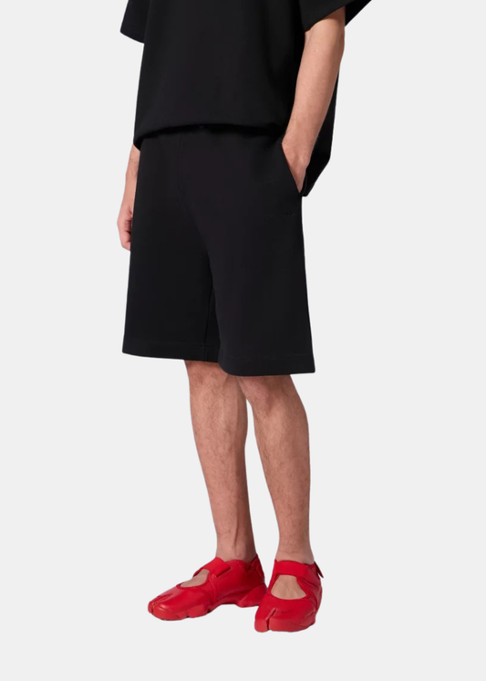 Gros plan latéral du short en molleton noir Gertrude Yann porté avec la main dans la poche.